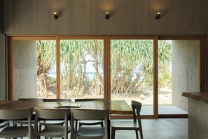 Outside the large wooden window, you can see the shadows of the Madagascar Pandanus trees. The splashes of the waves shining in the distance are just like a painting.
