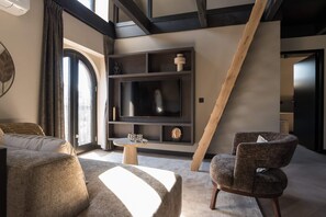 Rear-view of living space, with a rug, TV table, and the stairs to access the upstairs bedroom