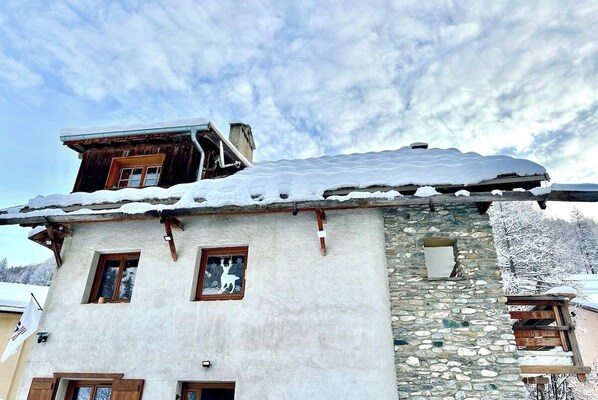 The charming chalet, nestled amidst a snowy landscape, is a picturesque setting for a tranquil getaway. The snow-dusted roof and the surrounding trees add to the winter wonderland ambiance. The whitewashed walls with wooden accents create a warm and invit