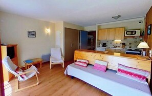 This inviting living area features a comfortable sofa bed, perfect for relaxing after a day of exploring the surrounding mountains. The sofa bed is situated near a large window, allowing for plenty of natural light and views of the picturesque alpine vill