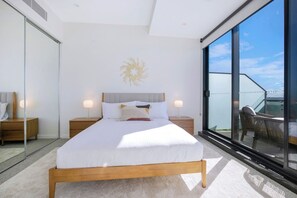 The primary bedroom includes a queen-size bed and large windows capturing elevated city views, as well as a pristine ensuite. 
