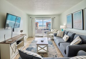 Bright open living space with comfy sofa, Smart Tv, and balcony