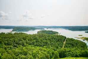 Stunning view of a serene lake surrounded by lush green forest and rolling hills, perfect for a peaceful retreat.