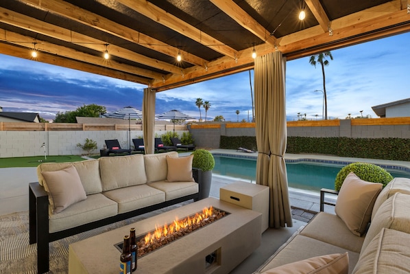 Cozy outdoor seating area with a fire pit and poolside views, perfect for evening gatherings