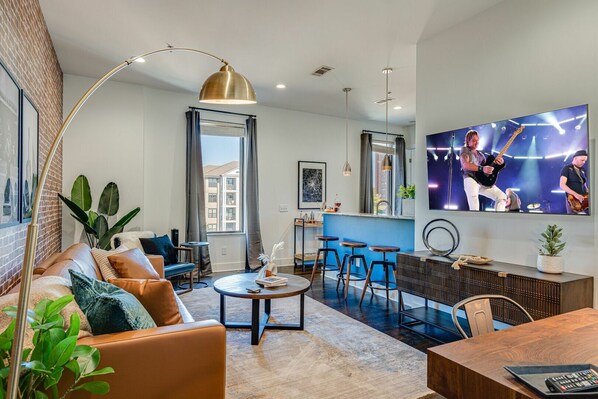Unit 1: Bright and open living area with designer furnishings and smart TV.
