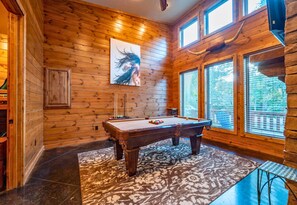 Enjoy some friendly competition in the spacious game room, featuring a pool table and beautiful wooden interiors.