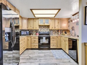 View of Kitchen Refrigerator, ample counter space, dishwasher, electric stove & oven, cooking spices, knife block, microwave, wood cabinetry, coffee maker