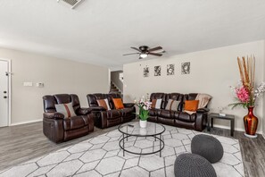 As you enter the home, you're greeted by a tastefully decorated living area, featuring a set of plush leather sofas that invite you to sink in and relax.