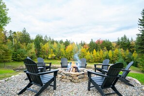 Stone firepit overlooking the pond with Adirondack chairs