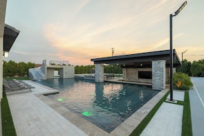 Outdoor modern pool area with adjacent covered patio and lounge chairs.