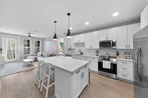 This is a modern and bright kitchen that opens into a living area