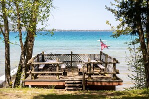 Your shared wooden deck with benches offers a picturesque view of a calm lake surrounded by lush trees.