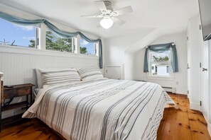 Primary bedroom with king bed, half bathroom, smart TV, closet and dresser for clothing storage, and ocean views!