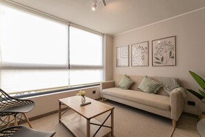 Relax in this cozy living room with modern decor, natural light, and a touch of greenery, perfect for unwinding after a day of exploring.