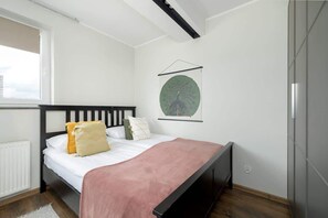 Double bed with dark wooden frame, large wardrobe. A poster hangs above the bed. 
