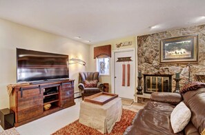 Unwind in the spacious living room, complete with a plush sofa, stone fireplace, and a smart TV, creating an inviting atmosphere for movie nights or cozy gatherings.