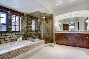 Indulge in the spa-like bathroom, featuring a large soaking tub, separate walk-in shower, and elegant stone detailing for a touch of luxury.