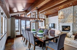 Host memorable dinners in the sophisticated dining room, complete with a grand dining table, stylish chairs, and a cozy stone fireplace creating a warm ambiance.