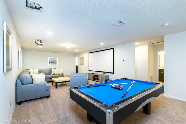 Stylish game & movie room with pool table, projector, & cozy seating