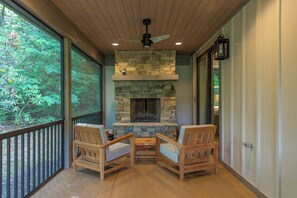 Screened-in porch with outdoor dining, wood-burning fireplace, and open-air deck