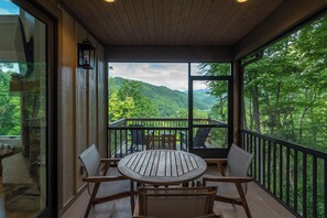 Screened-in porch with outdoor dining, wood-burning fireplace, and open-air deck