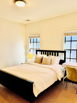 Large bedroom with queen bed and desk for working at home.