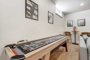 Cozy game room with shuffleboard table and comfortable seating area for relaxation and fun.