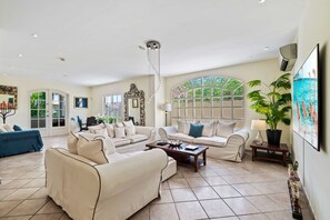 - Spacious living room featuring a smart TV, comfortable seating, and elegant décor - Large windows flood the room with natural light, creating a bright and airy atmosphere - A perfect blend of style and comfort for relaxation or entertainment