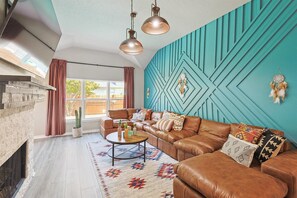 With an elegant air of “boho meets modern”, this stylish living room features an oversized L-shaped sectional, a bold accent wall, and a wall-mounted TV.