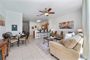 Area featuring a cozy sofa and a glass table, ideal for relaxation - Modern kitchen with bar seating, providing a perfect spot for casual meals - Elegant dining space with a round glass table, creating a welcoming environment for gatherings