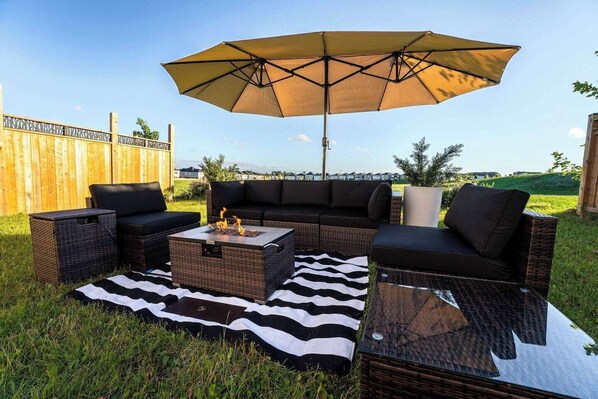 Escape to serenity in our rental space with a spacious backyard oasis, complete with a cozy couch and umbrella for ultimate relaxation and enjoyment