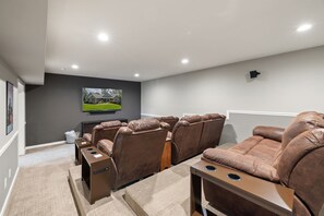 A cozy home theater with tiered seating, plush recliners, and a convenient bar area, perfect for movie nights and entertaining guests.