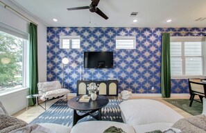 Living room with TV, ceiling fan, and windows with room darkening shades