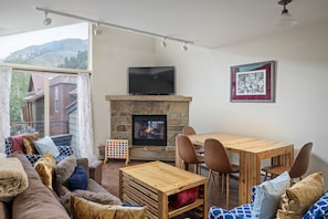 Cozy living room area with seating, flat screen TV, gas fireplace and games for the whole family