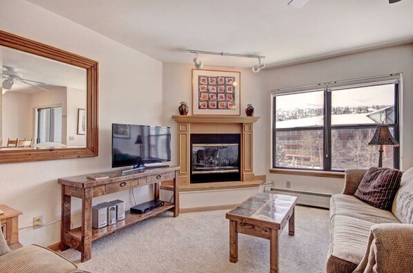 Unwind in the inviting living room with plush seating, a flat-screen TV, and large windows offering scenic views.