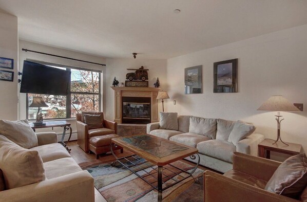 Bright and airy living room with comfortable seating, a fireplace, and large windows for natural light.