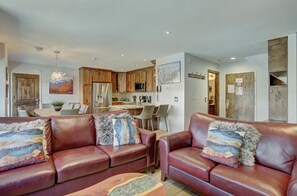 Welcoming living room with leather sofas, a flat-screen TV, and access to the kitchen for seamless entertaining.