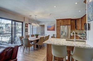 Open-concept dining and kitchen area with modern furnishings and large windows for a bright and airy feel.
