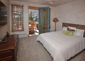 Rest comfortably in the inviting bedroom, which includes a king-sized bed, cozy decor, and direct access to the outdoor deck.