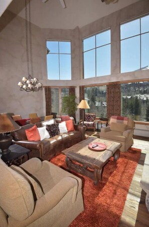 Gather in the bright living area, featuring high ceilings, panoramic views, and stylish furniture for a welcoming atmosphere.