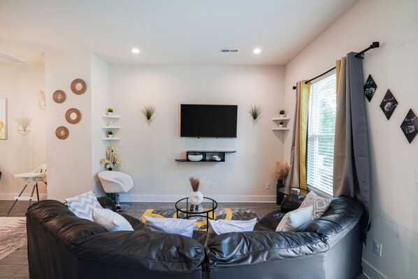 A plush couch and a smart TV. Living area with a balcony access.