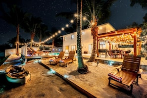 Our stunning patio with cozy loungers, dining area, and string lights creates the perfect ambiance for evening relaxation under the palm trees, just steps away from the tranquil canal waters.