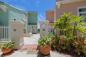 The entrance is adorned with terracotta pots overflowing with vibrant flowers, inviting you to explore the vibrant streets and immerse yourself in the tropical ambiance.