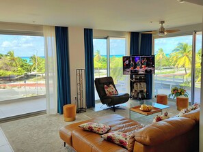 Living Room with large TV and lounge chair overlooking beach and ocean