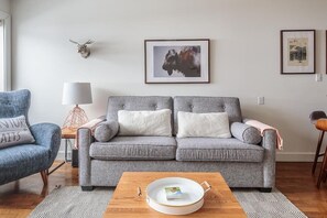 Stylish living room with gorgeous artwork, sofa bed, fireplace, and large TV