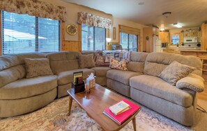 Welcome to the inviting living room, featuring a plush curved sectional couch perfect for family gatherings. Enjoy cozy evenings with the TV in view and easy access to the kitchen.