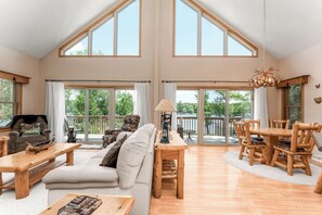 The open floor plan connects the living room, dining room, and kitchen, with stunning lake views and natural light. A cozy gas fireplace and custom log furniture create a warm space for gathering. Step onto the wrap-around deck to enjoy your morning coffee