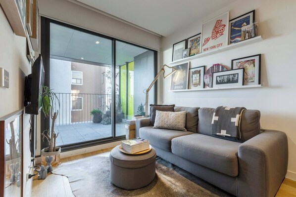 Modern living room with plenty of artwork, cool accessories and access to the large balcony, as well as a comfy sofa and TV