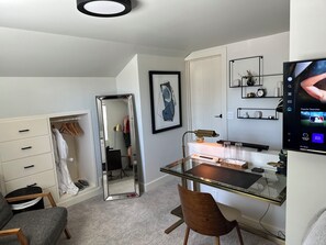 Open concept room with double bed, TV, closet, desk, TV, chargers and Alexa