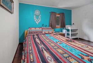 2nd bedroom’s queen bed, large headboard, bedside table, baby changing table.